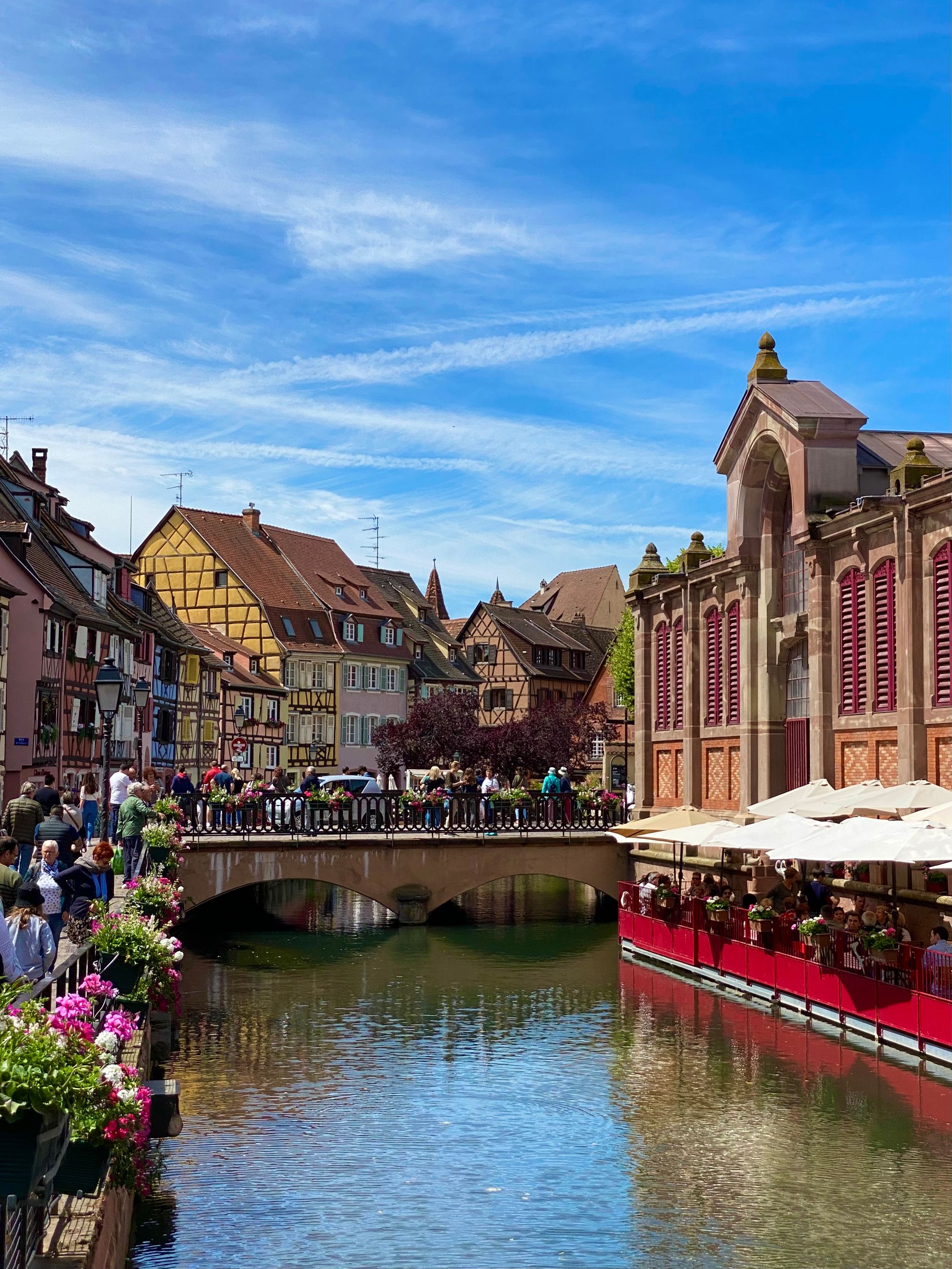 Colmar old town with beautifully decorated old building and many, many people enjoying the sun