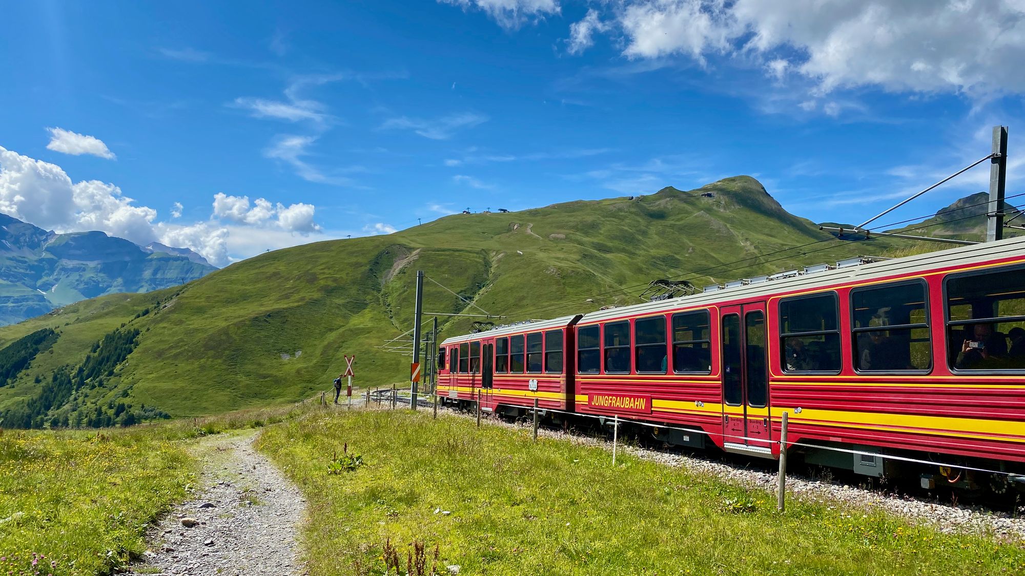 A red train crossing a tipical swiss landscape