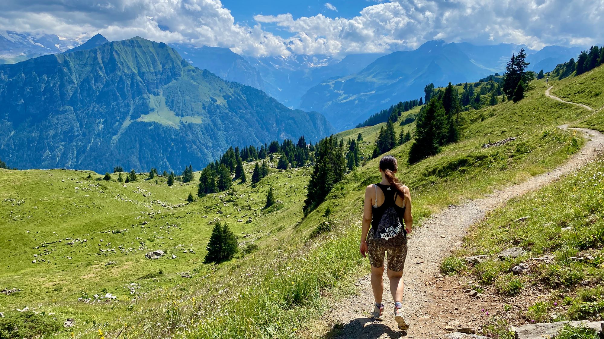 Silvia walking down on a trail with mountains and valleys in the background